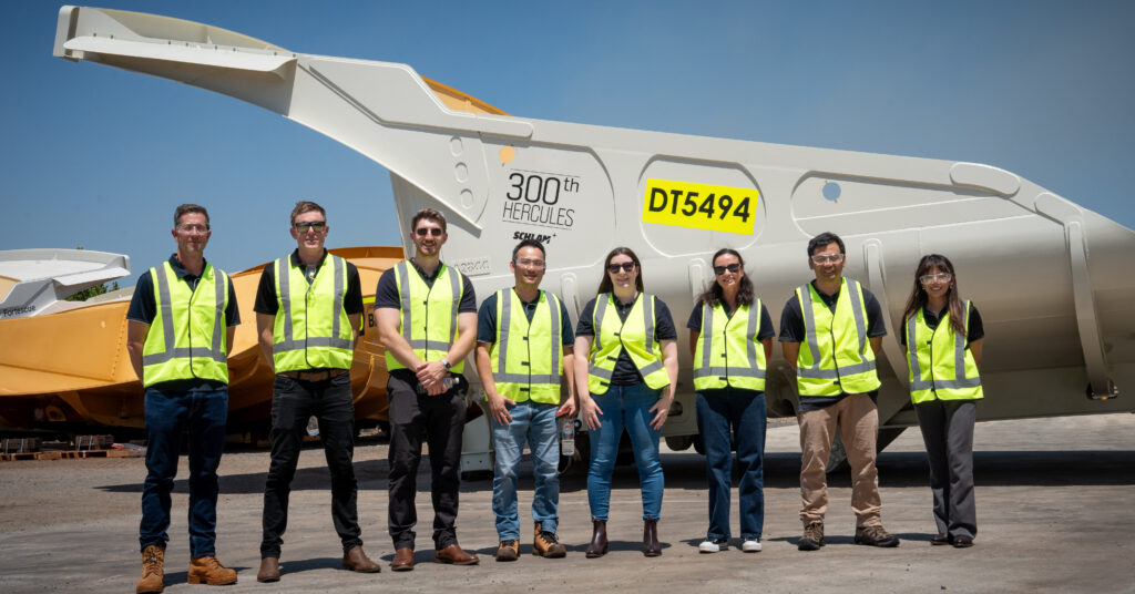 The Fortescue and Schlam teams in high vis, posing in front of Fortescue's 300th Hercules Truck Bed at Schlam's Forrestfield facility.